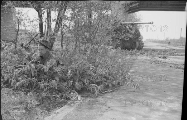 The British Army in North-west Europe 1944-45 A camouflaged Sherman Firefly of the Irish Guards and infantry guard a sec