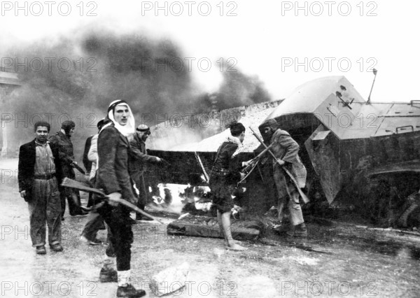 Israel / Palestine: Palestinian fighters beside a burned-out Israeli Haganah supply truck near Jerusalem, Arab-Israeli W