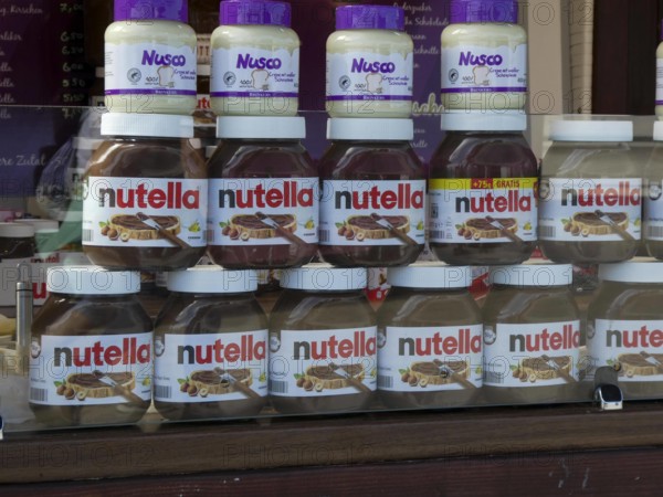 SYMBOLBILD-10.AUGUST 24 - VERZEHR-ESSEN Nutella Glaeser in Doppelreihe stehen in einem Verkaufswagen darauf eine Reihe weisse Creme Nusco Glaeser Nutella ist eine Nuss-Nougat-Creme des italienischen Süßwarenherstellers Ferrero. SH Deutschland *** Symbol image 10 August 24 Consumption Food Nutella Glaeser in double row Standing in a Sales trolley on it a Series Whites Cream Nusco Glaeser Nutella is a Nut Nougat Cream of Italian Confectionery manufacturer Ferrero SH Germany