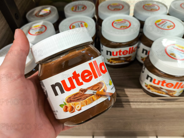 Arco, Italy - July 16, 2024: A man holds a jar of Nutella from Ferrero in an Italian supermarket *** Ein Mann hält ein G