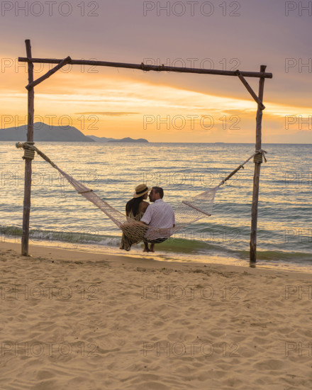 Men and women watching sunset from a hammock on the beach in Pattaya Thailand Ban Amphur beach Men and women are watchin