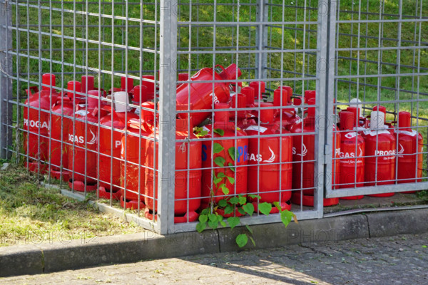Flüssiggas, rote Gasflaschen der Firma PROGAS hinter einem Sicherheitsgitter *** Liquid gas, red Gas cylinders the Compa