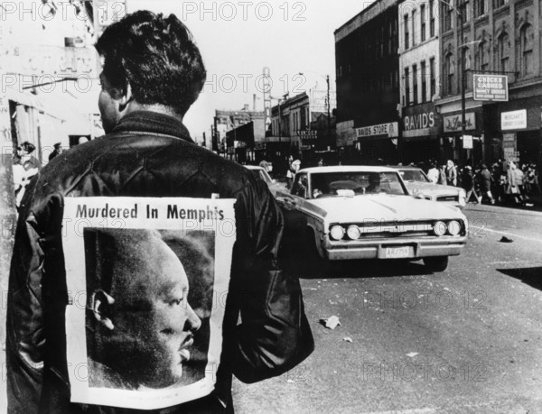 A man wers a placard proclaiming the death of Dr Martin Luther King cut from a local newspaper