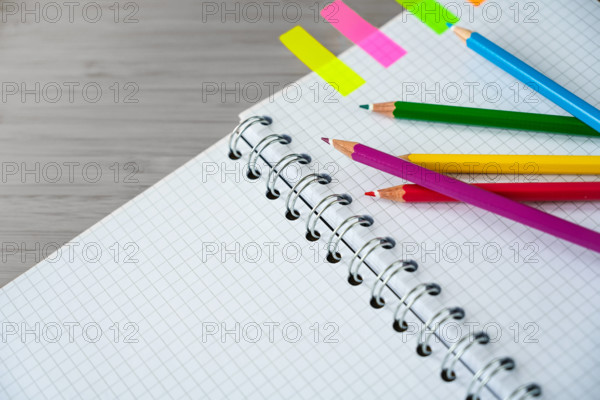 Buntstifte auf einem Teil eines Spiralheftes und bunte Marker auf einem grauen Schreibtisch, kreatives Arbeiten oder Schulmaterial, Kopierraum, ausgewählter Fokus
