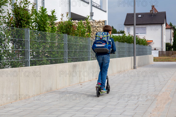 Symbolbild: Schulkind mit Tretroller auf dem Schulweg (model released) *** Symbolic image of a schoolchild with a scoot