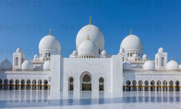 Blick auf die Große Scheich-Zayed-Moschee in Abu Dhabi aus weißem Marmor mit Blumen aus Edelsteinen im Design und schönen Spiegelungen im Wasser