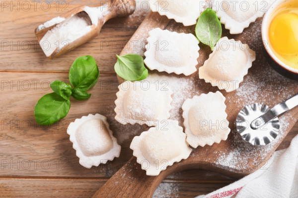 Ravioli italienisches Essen. Leckere hausgemachte Pasta Ravioli mit Mehl, Tomaten, Eier und Grüns Basilikum auf hölzernen Hintergrund. Prozess der Herstellung italienischer Ravioli. Lebensmittel Kochen Zutaten Hintergrund. Ansicht von oben.