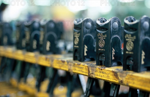 ITALIE. L'USINE D'ARMEMENT BERETTA, L'UNE DES PLUS CELEBRES DANS LA FABRICATION D'ARMES DE CHASSE OU DE GUERRE. RANGEES DE CULASSES ATTENDANT D'ETRE MONTEES SUR LES ARMES.