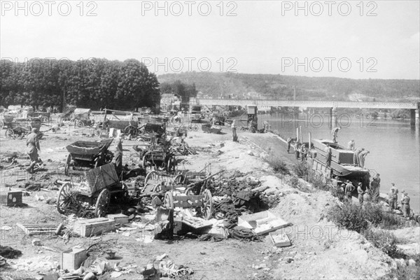 D Day. German Army retreats from the River Seine. 
British troops survey the remains of vehicles and suplies left by the German Army on the banks of the river Seine