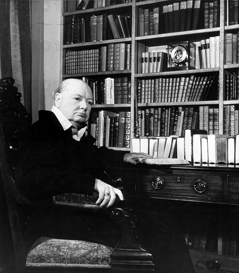 Winston Churchill  sitting  in front of a large bookcase 1951