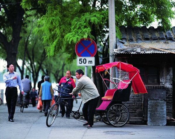 A man earns his living with the traditional pedicab by a hutong of Beijing,China