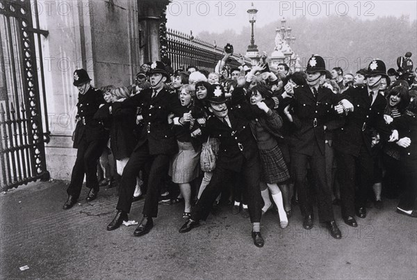 POLICIAS SUJETANDO A LAS FANS DE LOS BEATLES EN EL EXTERIOR DEL PALACIO DE BUCKINGHAM - 1965
This image is not downloadable. Contact us for the high res.