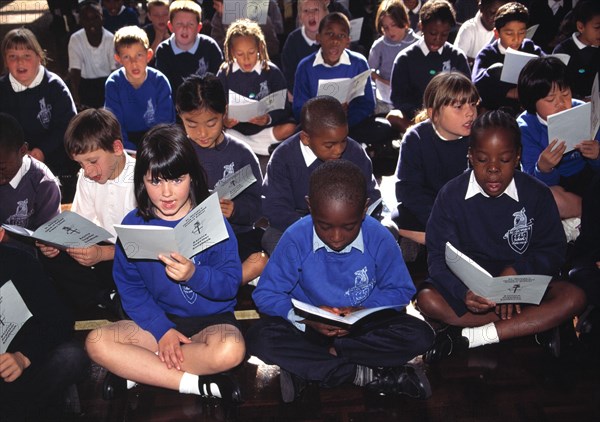 Class of mixed ethnic backgrounds attend a Christian assembly in a south London school