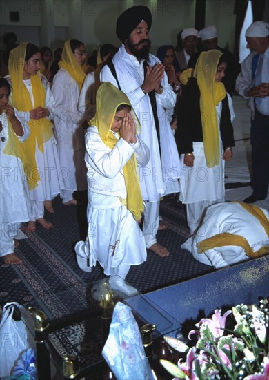 People pay their respects before the Guru Granth Sahib