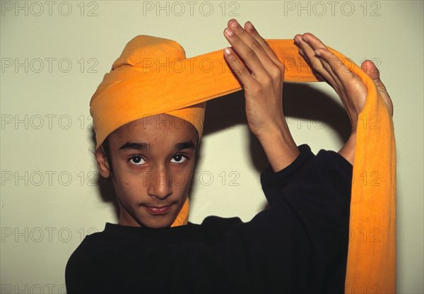 A Sikh youth tying the turban worn by all Sikh men.