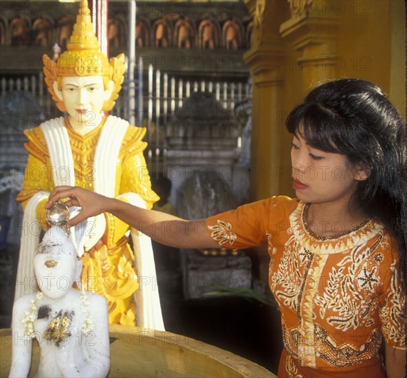Purifying statue of the Buddha on the occasion of Wesak, woman in the Shwedagon Pagoda in Yangon, Myanmar