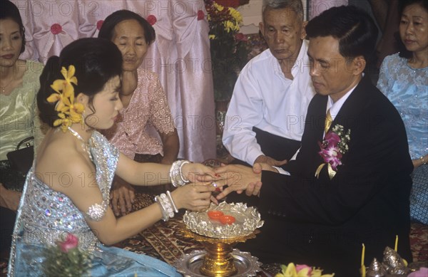 Khymer bride places ring on new husband`s finger Cambodian wedding ceremony