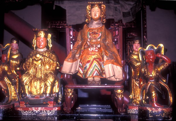 Kuan Yin, or Guan Yin, the Taoist Goddess of Mercy and Compassion and guardian of sea-farers. Temple altar flanked by less deities.