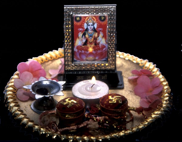 Puja tray with candle flowers and picture of Lakshmi