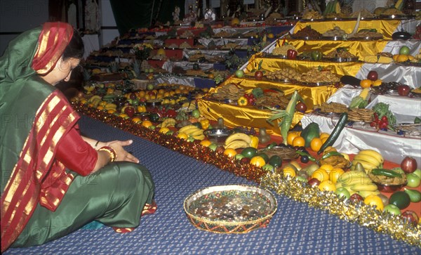 Hindu woman praying before temple offerings for Dibali Festival of Light, UK