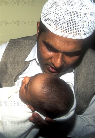 Father whispers opening words of the Muslim prayer in his newborn baby`s ear