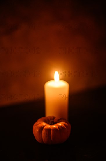 Lit candle and pumpkin