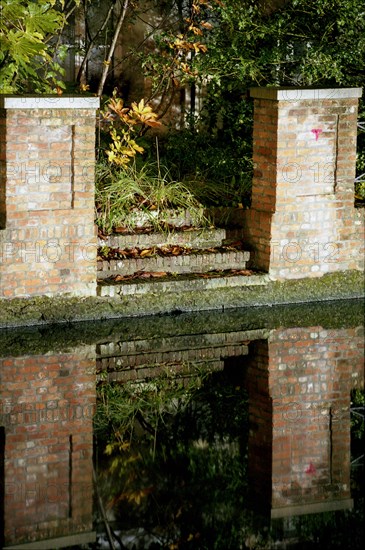 Bruges de nuit : murs de briques et escalier se reflétant dans le canal en automne, Quai du Dijver