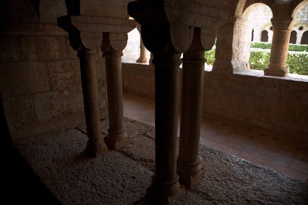 Provence811 Abbaye du Thoronet, le cloître vu depuis la salle capitulaire : arcades géminées, oculus et chapiteaux, vue sur le jardin du cloître