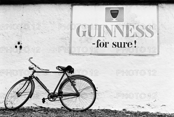 Bicyclette contre le mur d'un pub, sous une publicité pour la bière Guinness.
Comté de Kildare, Irlande, 1985