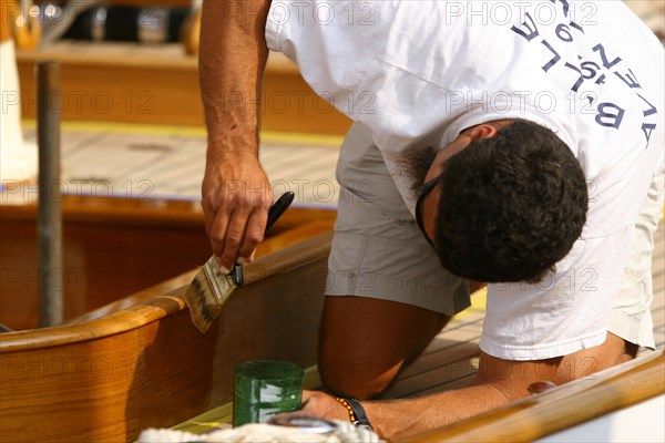 A sailor varnishes his boat