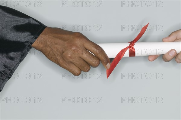 Closeup of hand receiving diploma.