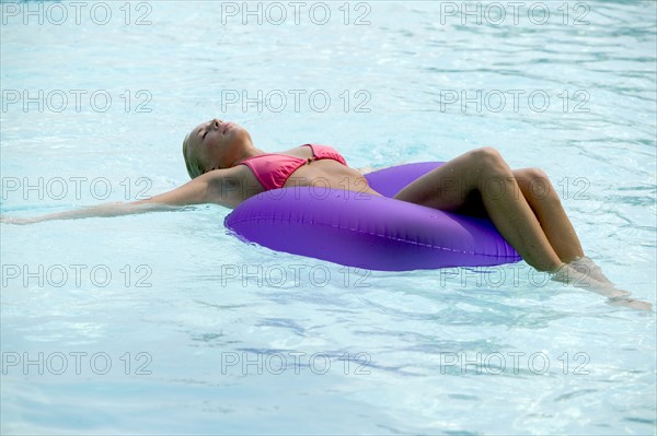 A young woman floating in a pool.