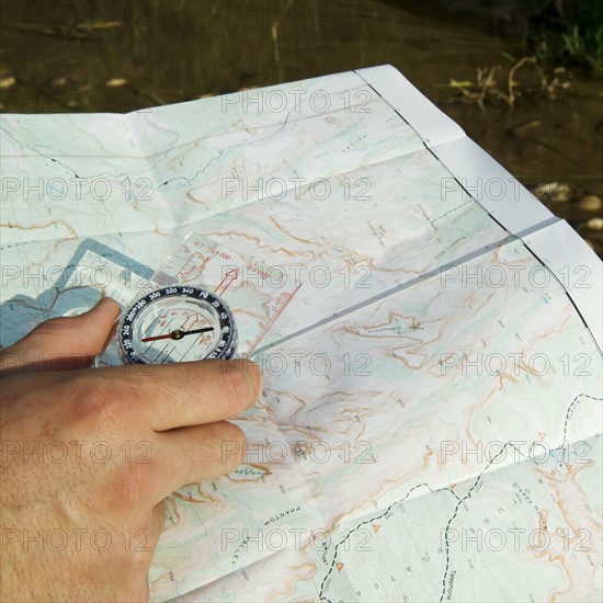 Hand holding a compass and map.