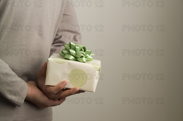 Man hiding a gift behind his back.
