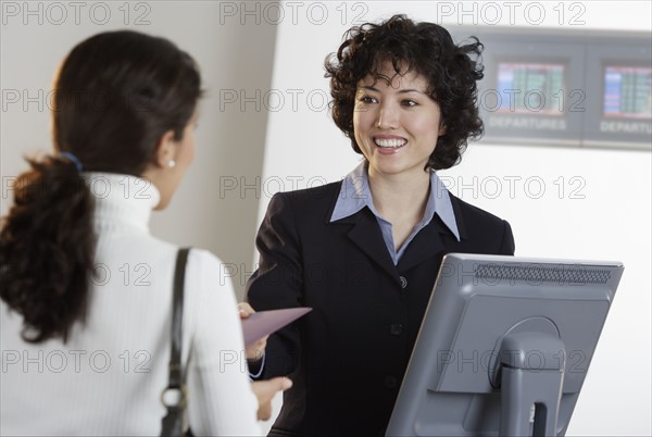 Airline employee assisting a customer at ticket counter.