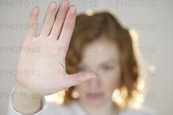 Redhead with flat palm raised.