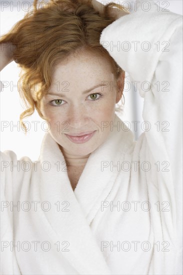 Woman in bathrobe holding hair up.