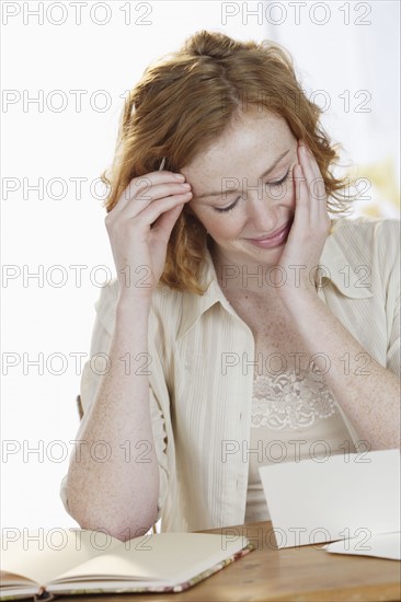 Smiling woman reading at table.