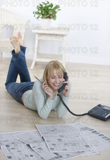 Woman with newspaper talking on phone.