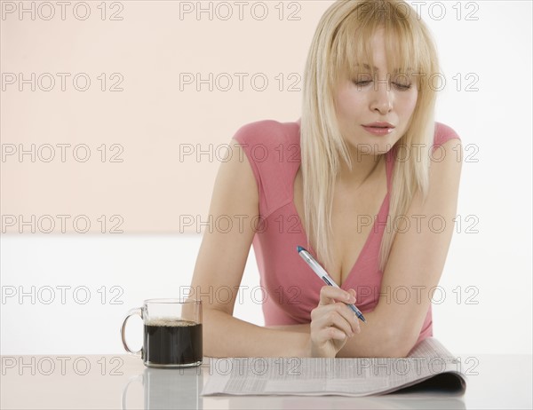 Woman at table with newspaper.