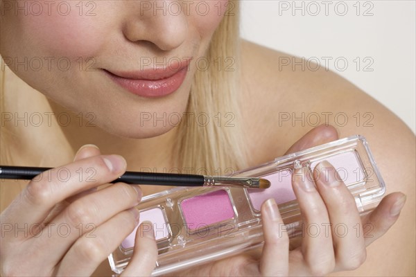 Woman's hands with cosmetics and brush.