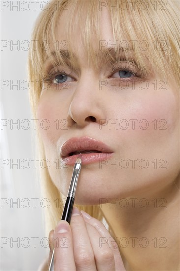 Woman applying lipstick with brush.