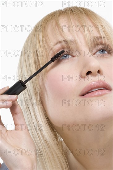 Woman looking up applying mascara.