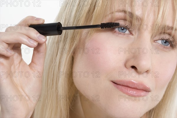 Woman looking sideways applying mascara.