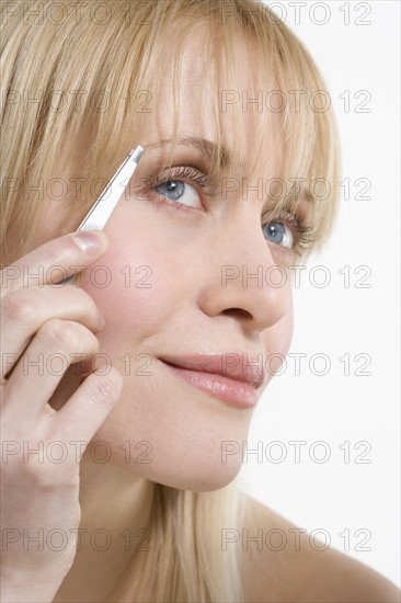 Woman plucking eyebrows.