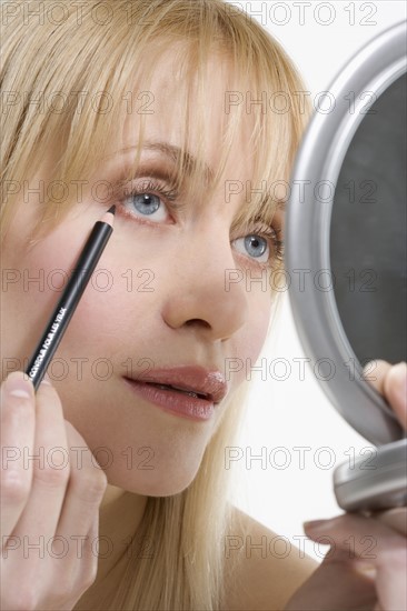 Woman with mirror and eyeliner.