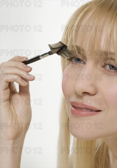 Smiling woman using cosmetic brush.