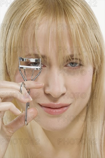 Woman using eyelash curler.