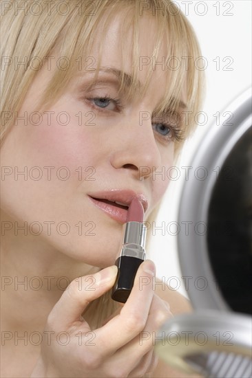 Woman with mirror applying lipstick.