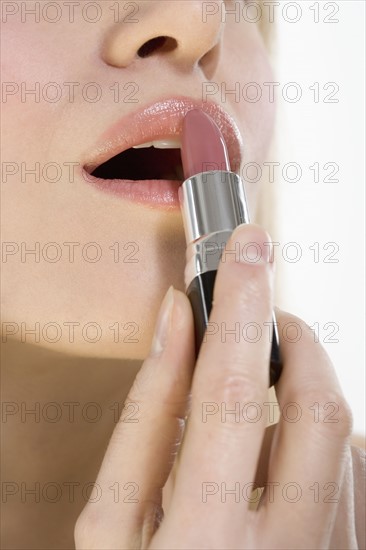 Closeup of lips with lipstick tube.